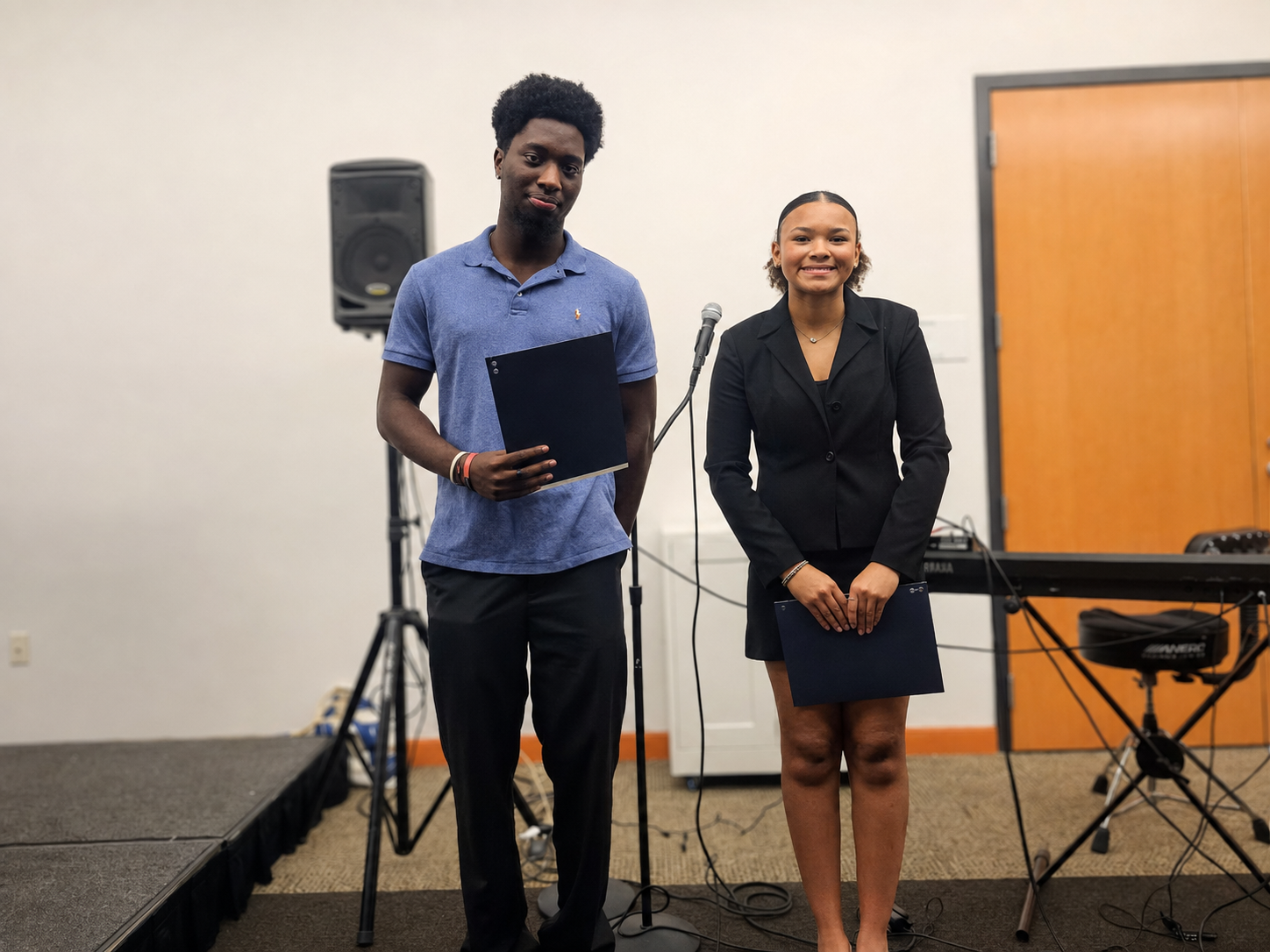 Two scholarship recipients standing with their award folders at the banquet