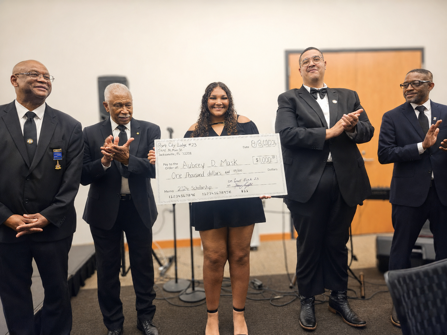 A student receiving a large ceremonial scholarship check